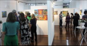 Em setembro de 2022, Tonho da Bahia ocupava o centro das atenções na reabertura da Galeria de Arte Carlo Barbosa, do Centro Universitário de Cultura e Arte (Cuca), da Uefs. Os quadros de José Antônio dos Santos Pereira levavam para aquele espaço as cores e o cotidiano de Feira de Santana. Quatro anos depois, cabe perguntar à Universidade o que ocorreu com a trajetória artística que a própria instituição ajudou a revelar.Auxiliar de serviços gerais e trabalhador terceirizado, Tonho encontrou no ambiente onde trabalhava uma oportunidade de formação. Em 2014, aos 54 anos, começou a participar das oficinas do Cuca. Aprendeu desenho com Avelina Bitencourt e pintura com Jorge Galeano. Em 2017, uma obra foi selecionada para a Bienal Internacional de Arte Naïf Totem Cor-Ação, em Socorro, no interior de São Paulo. Tonho com o reitor Evandro do Nascimento Na exposição de 2022, o então reitor Evandro do Nascimento afirmou que a iniciativa “cumpre um papel de valorizar a obra de um artista da terra”. Também destacou que Tonho “tem um estilo muito próprio de uso de determinadas cores, mas com a temática muito presente na nossa realidade de Feira de Santana e de nossa região”. Defendeu, ainda, esforços de valorização “dos nossos potenciais”. Há pelo menos um registro institucional posterior. A programação da Feira de Graduação da Uefs, em outubro de 2024, anunciou a exposição de uma obra de Tonho entre as atividades do Cuca. Esse anúncio, entretanto, não esclarece como prosseguiu a produção do artista, quais oportunidades recebeu desde então ou qual relação mantém atualmente com o centro de cultura. Ou se ele foi convidado e esteve presente. Esquecimento  Tonho continua pintando? Participa de oficinas e exposições? Permanece trabalhando na Universidade? Houve transferência do Cuca para o campus e, em caso positivo, por qual motivo? Que acompanhamento e incentivo à produção artística foram mantidos? São perguntas dirigidas à Uefs e ao Cuca sobre uma trajetória apresentada publicamente como exemplo dos resultados da formação cultural. A história de Tonho merece continuidade e visibilidade. Ao reconhecer naquele trabalhador um artista capaz de representar Feira de Santana, a Universidade mostrou o alcance de uma oportunidade. Agora, não pode simplesmente deixar no esquecimento. Cabe esclarecer os caminhos dessa trajetória e quais possibilidades existem para que o público volte a encontrar Tonho da Bahia e a produção dele. 18/10/26